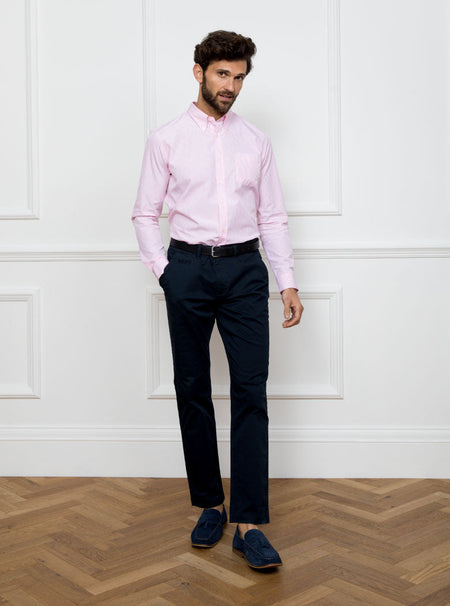 Man wearing a long sleeved shirt with a pale pink and white thin stripe pattern made with 100% Oxford in a Thomas Mason fabric.